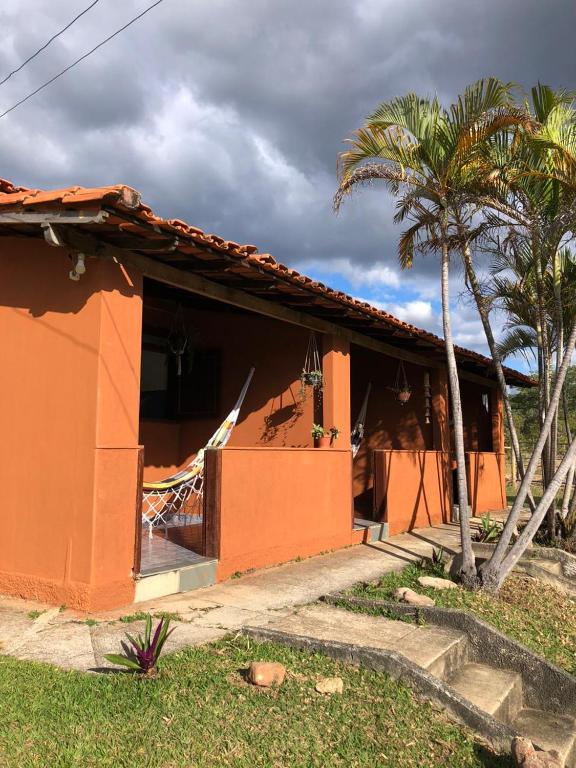 an orange house with a palm tree in front of it at Chalés Vale Encantado - Serra do Cipó in Jaboticatubas
