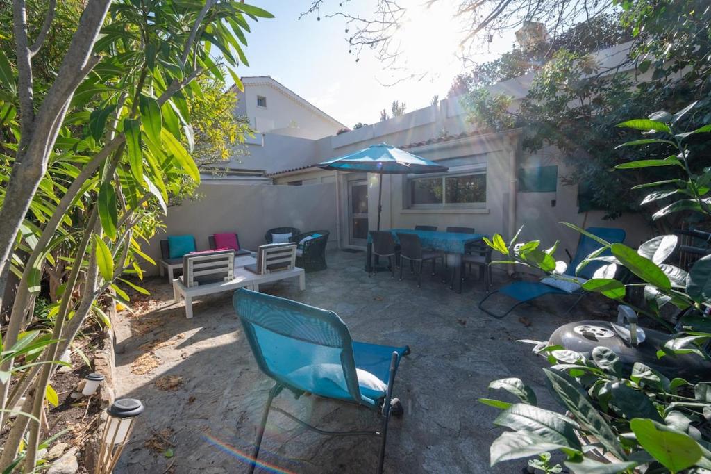 un patio avec des chaises, une table et un parasol dans l'établissement Unique résidence front de mer studio climatisé et jardin, au Lavandou