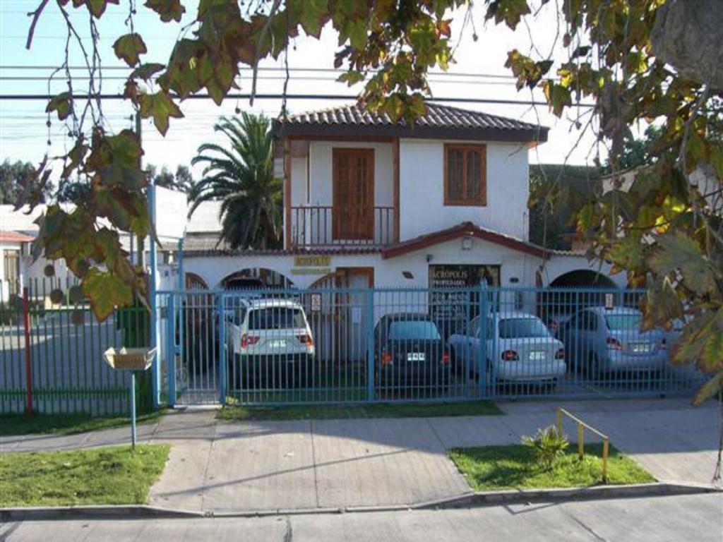 a house with cars parked in front of a fence at Acropolis Hostal in La Serena