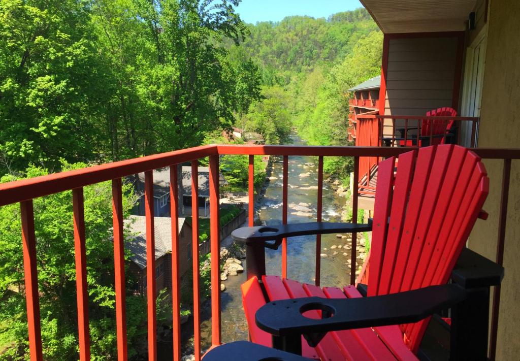 two red rocking chairs sitting on a porch with a view at Baymont by Wyndham Gatlinburg On The River in Gatlinburg