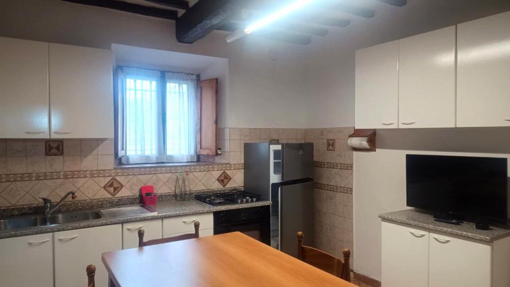 a kitchen with a refrigerator and a table in it at Casa Anna in Castellina in Chianti