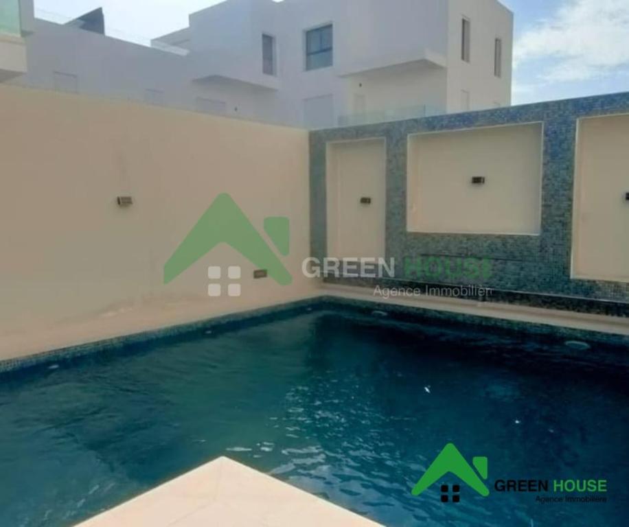 a swimming pool in front of a building with green houses at Green Hôte in Gammarth