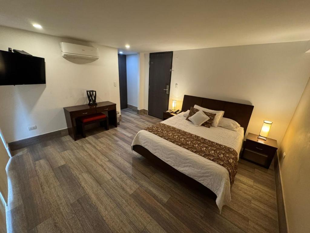 um quarto de hotel com uma cama e uma televisão em Vallclaire Suites em Barranquilla