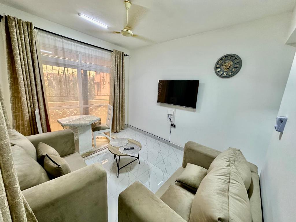 モンバサにあるHarmony 1 Bedroom Apartmentのリビングルーム(ソファ、壁掛け時計付)