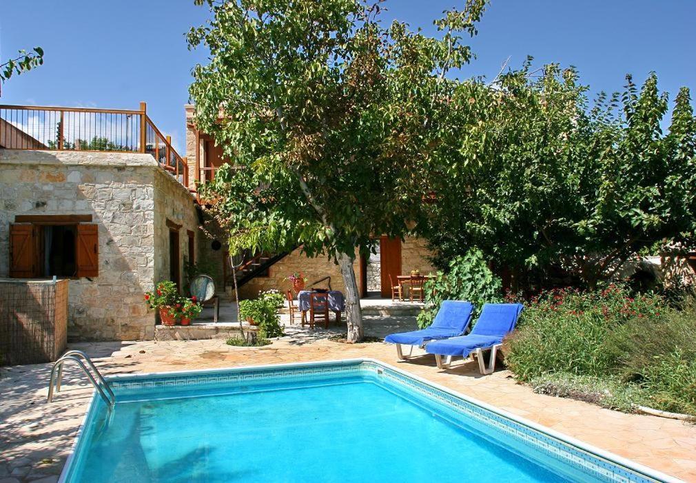 uma piscina com duas cadeiras azuis e uma casa em Narkissos Villa em Kallepia