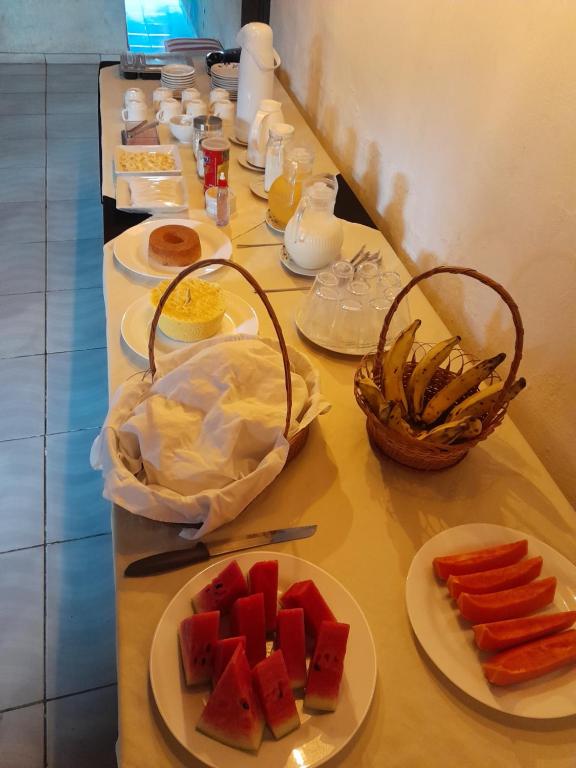 Una mesa larga con platos de comida encima. en Pousada lagoa azul, en Santo Amaro