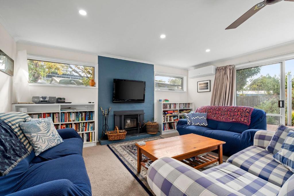 een woonkamer met twee blauwe banken en een tv bij The Abbey in Point Lonsdale