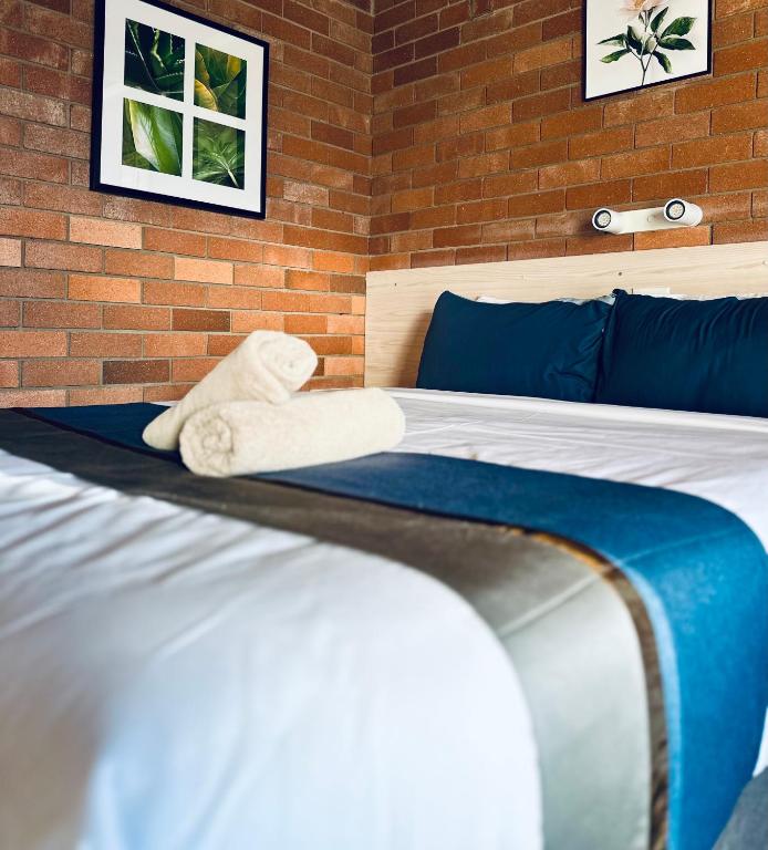 a bedroom with two beds with a towel on the bed at Red Chief Motel in Gunnedah