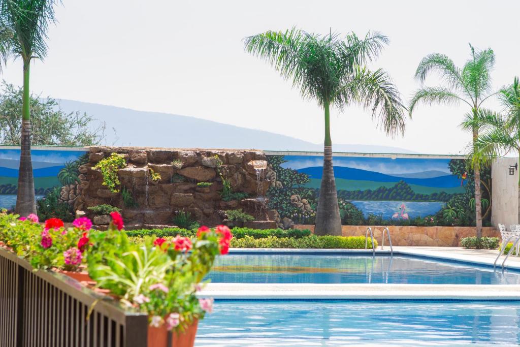 una piscina con palmeras y un mural en Hotel Kazmay, en Temixco