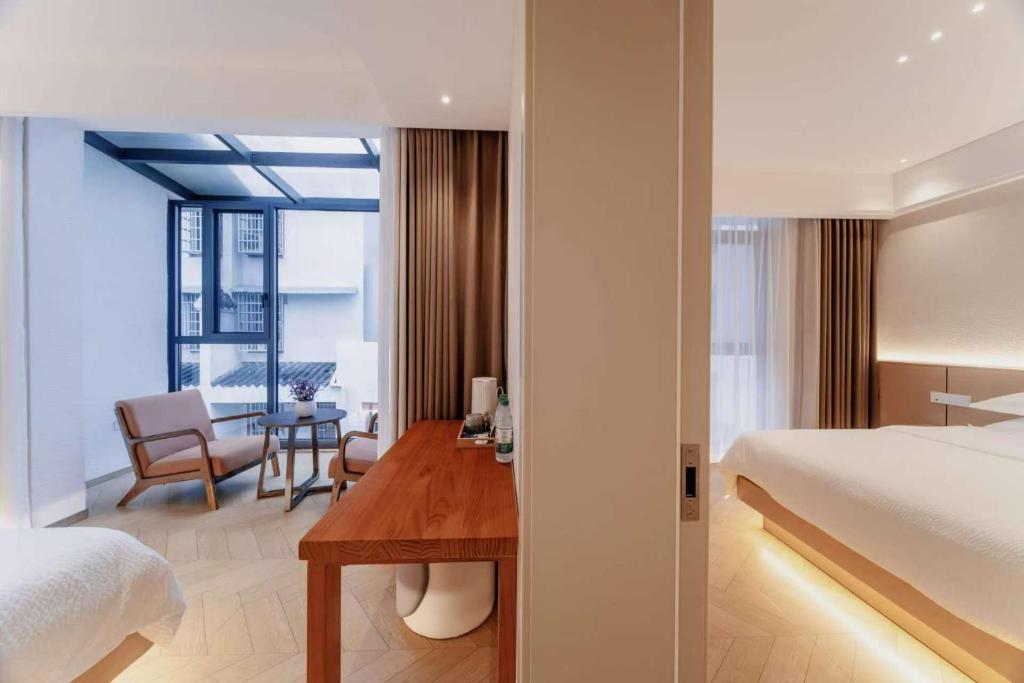 a hotel room with a bed and a desk and a table at Flower Whisperer Homestay Tianmenshan Store free airport and station pick-up in Zhangjiajie
