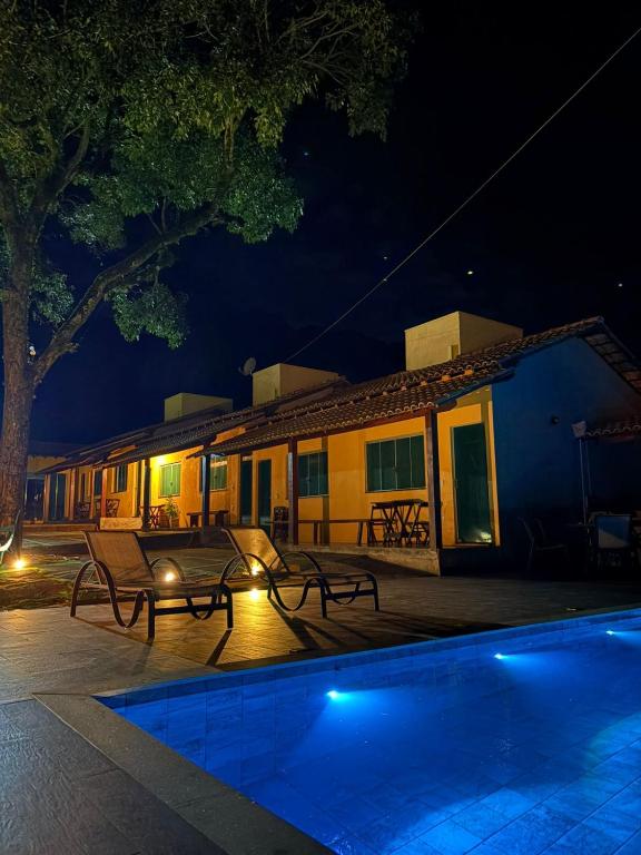 a house with a swimming pool at night at Pousada Ipê do Lago in Capitólio