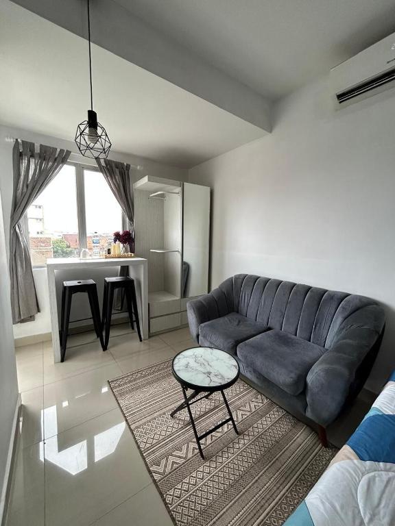 a living room with a blue couch and a table at 1BR Plus Sudirman Suite Apart by Metta in Bandung