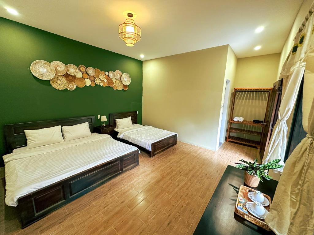 a bedroom with two beds and a green wall at Du Yen Garden Mang Đen in Kon Von Kla