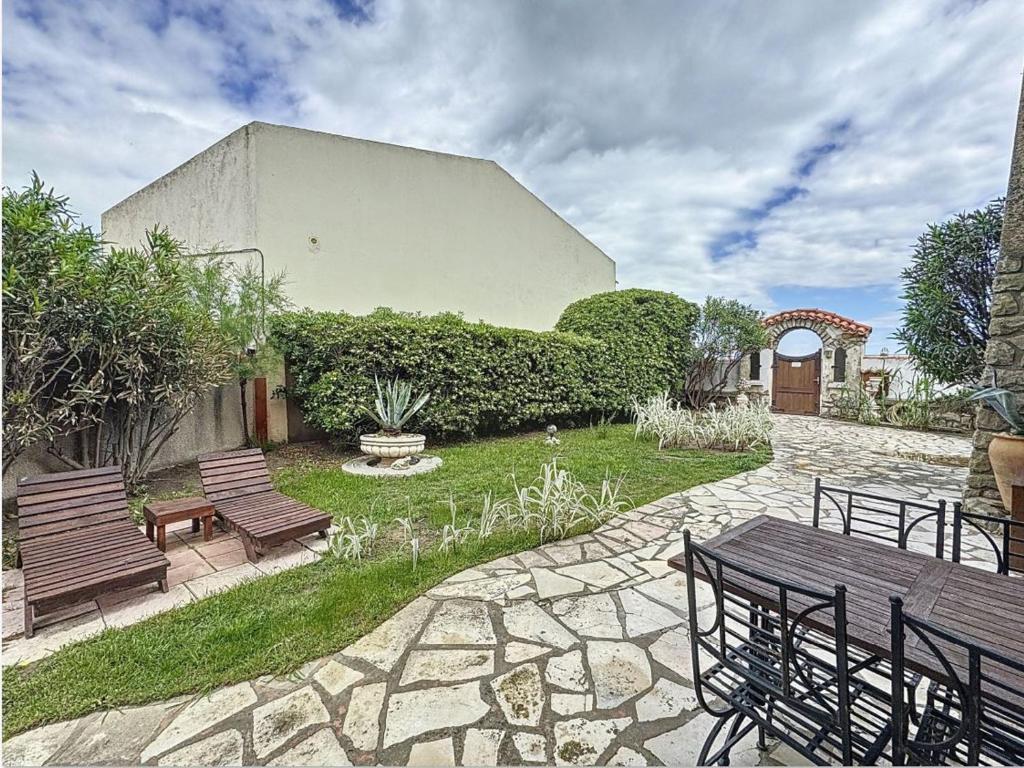 - un patio avec deux bancs en bois et un bâtiment dans l'établissement Appartement cosy pour 2, proche plage aux Saintes-Maries-de-la-Mer - FR-1-475-184, à Saintes-Maries-de-la-Mer