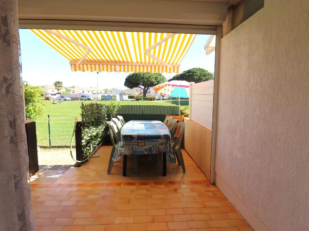une terrasse avec une table et des chaises sous une tente dans l'établissement Appartement rez-de-chaussée pour 6 pers, terrasse, proche plage - FR-1-307-286, au Grau-du-Roi