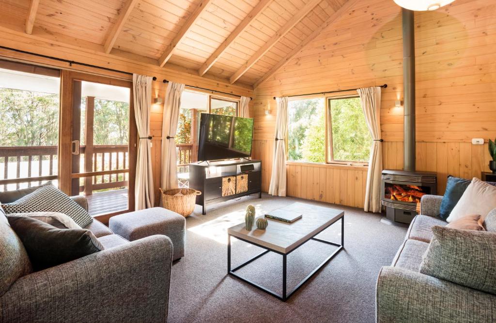 a living room with a couch and a tv and a table at Cosy Romantic Lodge, Perfect Couples Getaway in Sassafras
