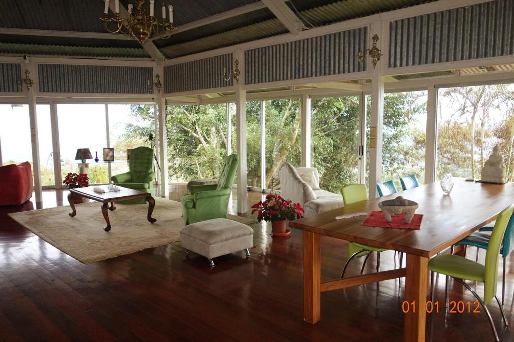 a living room with a table and chairs at Hacienda las Nubes in Turrialba