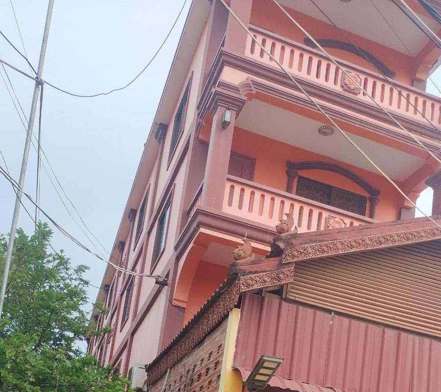 a pink building with a balcony on the side of it at UCS GUESt HOUSE in Siem Reap