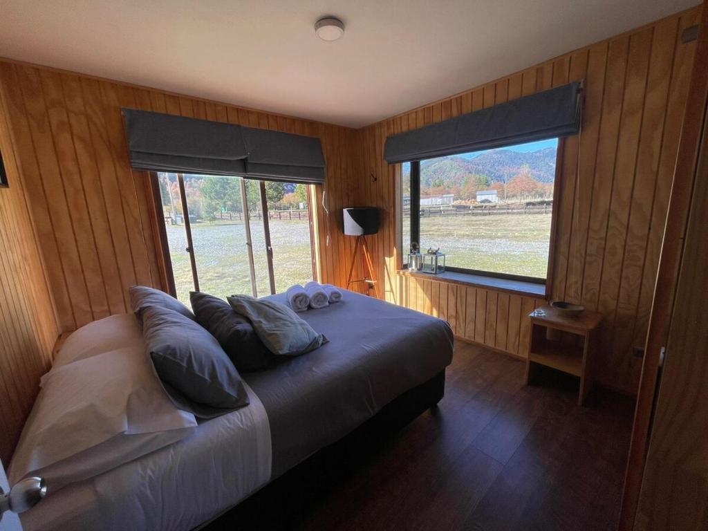 una camera da letto con letto con cuscini e ampia finestra di Cabaña Malalcahuello a Curacautín