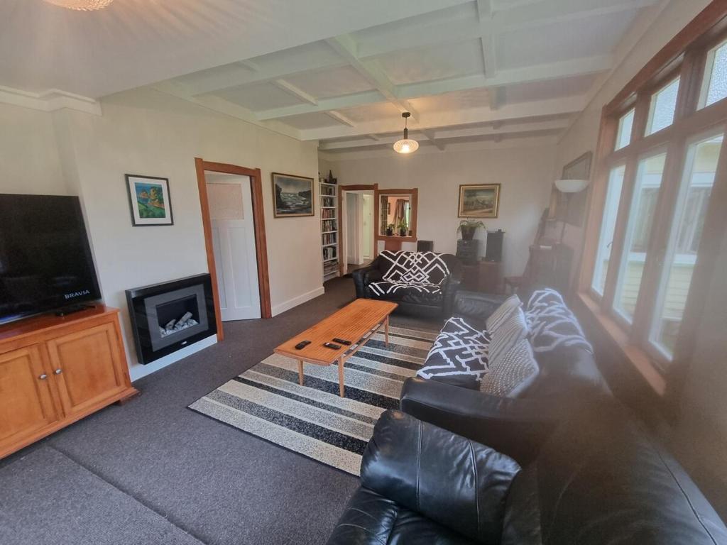 un salon avec un canapé en cuir et une télévision dans l'établissement Orira River Cottage, à Umawera