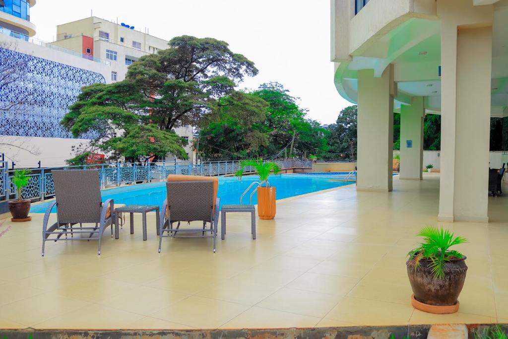 a patio with chairs and a table and a pool at Aramis Apparments in Nairobi