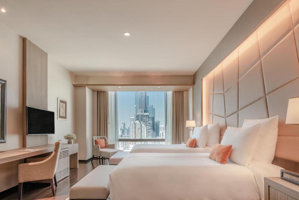 A twin room with two beds facing a bright Bangkok skyline.