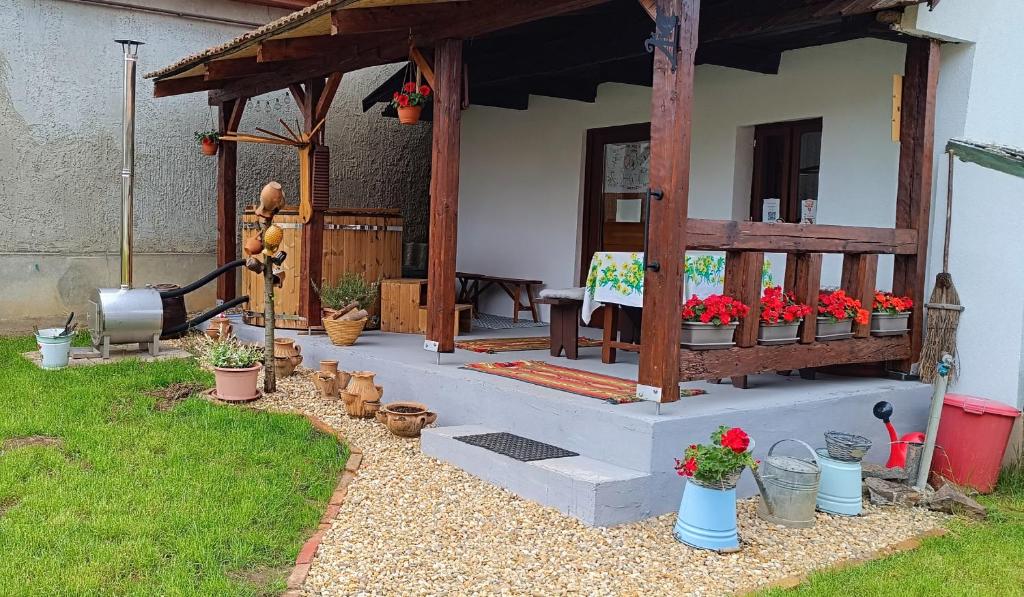 a garden with a wooden pavilion with flowers in pots at Vándor Kakas Vendégház dézsafürdővel in Recsk