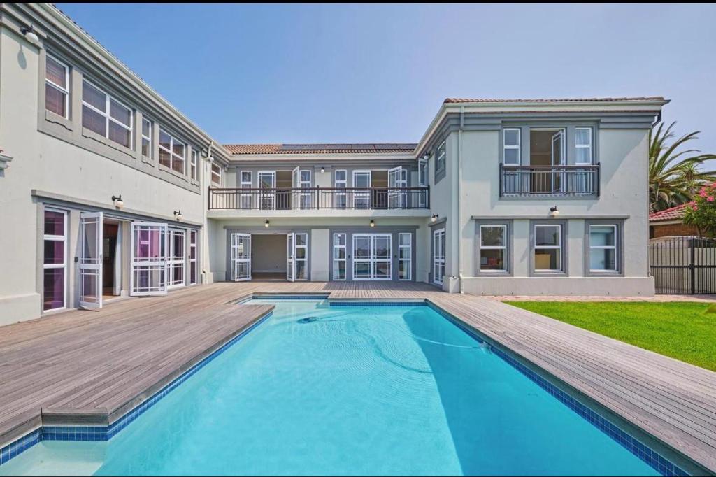 a large house with a swimming pool in front of a house at Cape Golf Villa in Cape Town