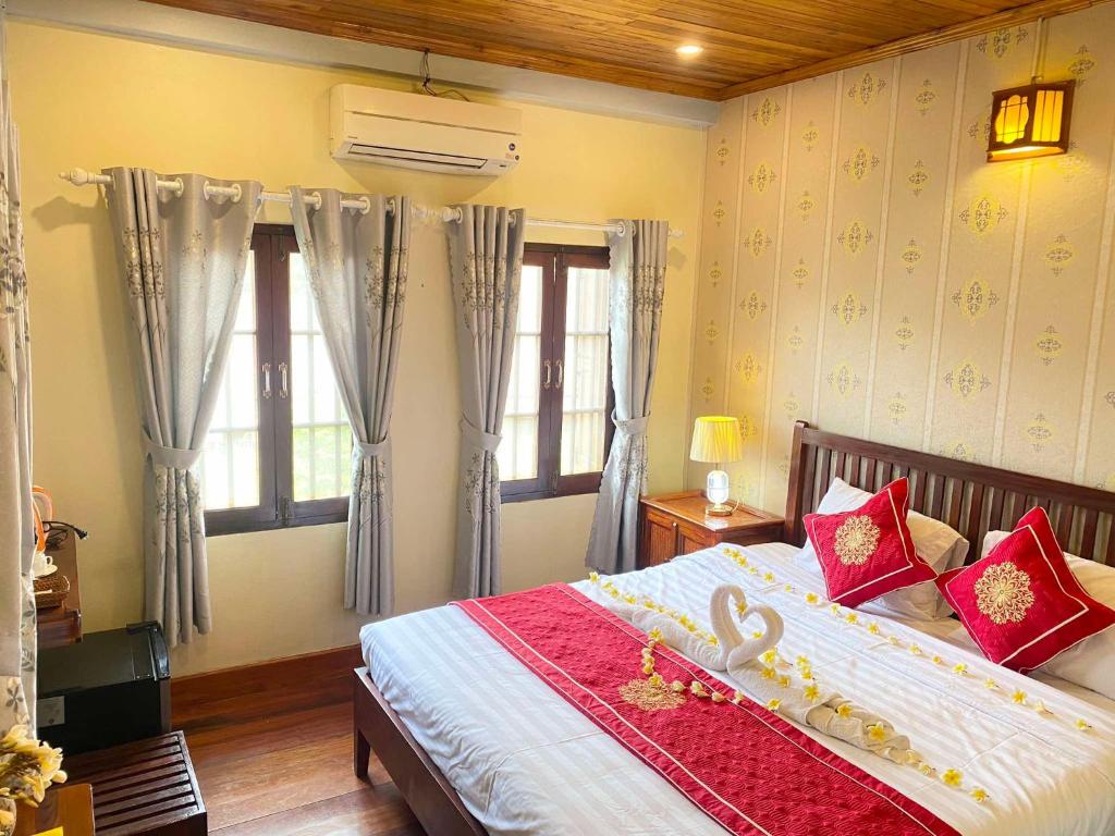 a bedroom with a large bed with red pillows at Golden Sun Hotel Luang Prabang in Luang Prabang