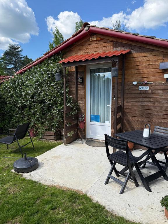 a table and chairs in front of a cabin at Chalet de campagne en Dordogne avec piscine in Saint Agne