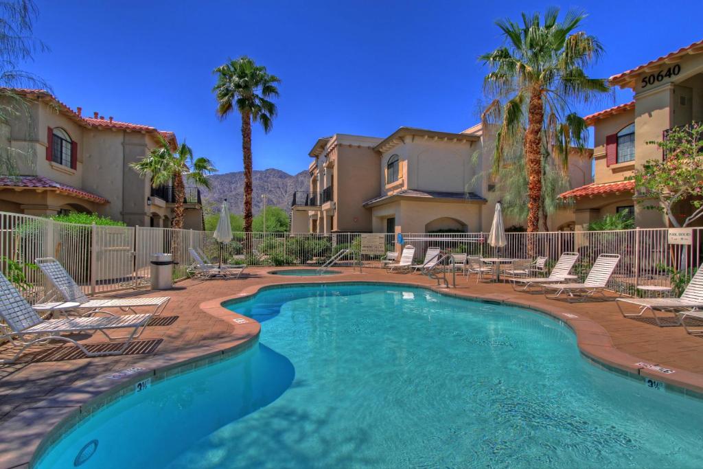 uma piscina com cadeiras e palmeiras em La Quinta Vacations Rental em La Quinta
