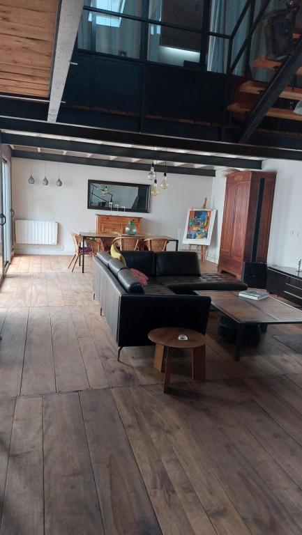 un salon avec un canapé noir et une table dans l'établissement Maison de ville, à La Celle-sous-Gouzon