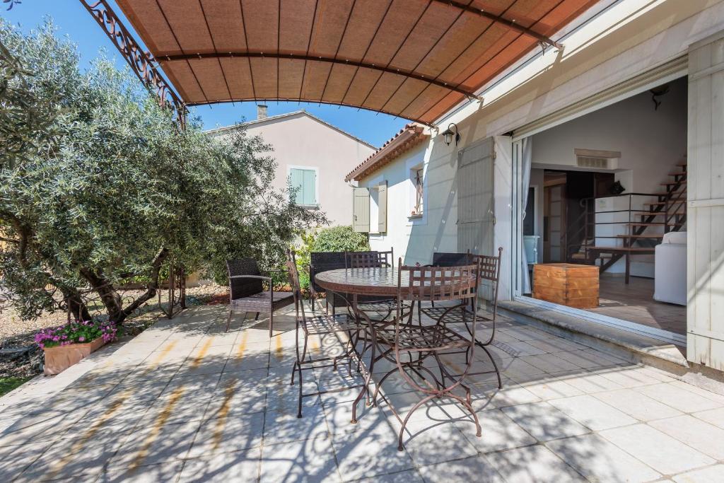 d'une terrasse avec une table et des chaises sous un auvent. dans l'établissement Lavande - maison climatisée avec grand jardin, à Cabrières-dʼAvignon