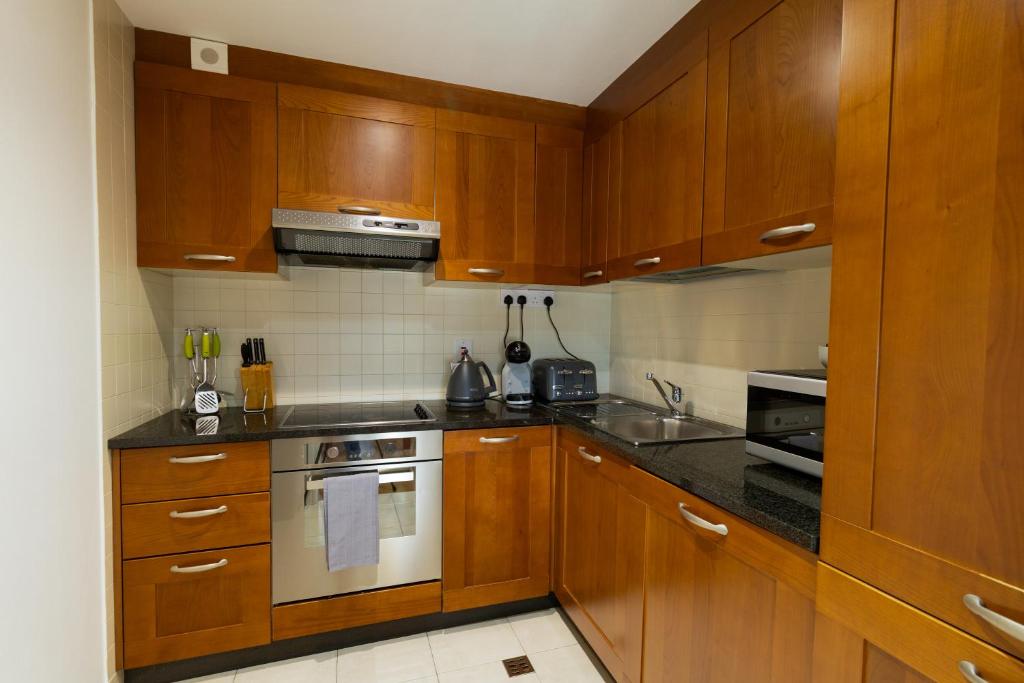 ゴールウェイにあるGeata na Cathrach - Galway Lakeside Apartmentsの木製のキャビネットとコンロ付きオーブンを備えたキッチン