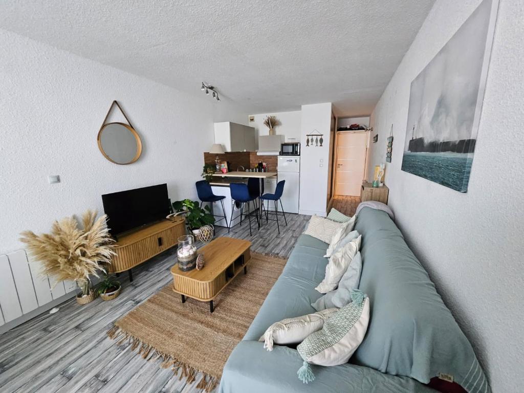 un salon avec un canapé bleu et une cuisine dans l'établissement La dolce vita, au Cap d'Agde