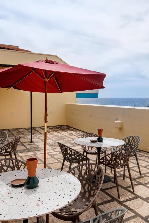 a patio with tables and chairs and a red umbrella at Palazzo Emanuele Luxury in Gallipoli