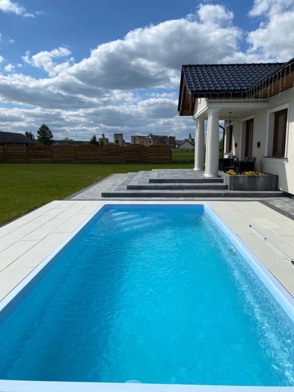 a blue swimming pool in front of a house at Dworek pod Krzyżtoporem Ujazd Agroturystyka- pokoje do wynajęcia in Iwaniska