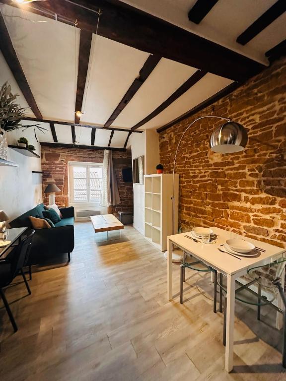 - un salon avec une table et un mur en briques dans l'établissement L Adresse Carnot - HYPERCENTRE - GARE - PARKING - HISTORIQUE, à Mâcon