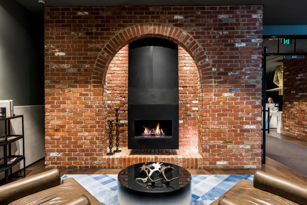 a brick fireplace in a room with a table at WRAP on Southbank in Melbourne