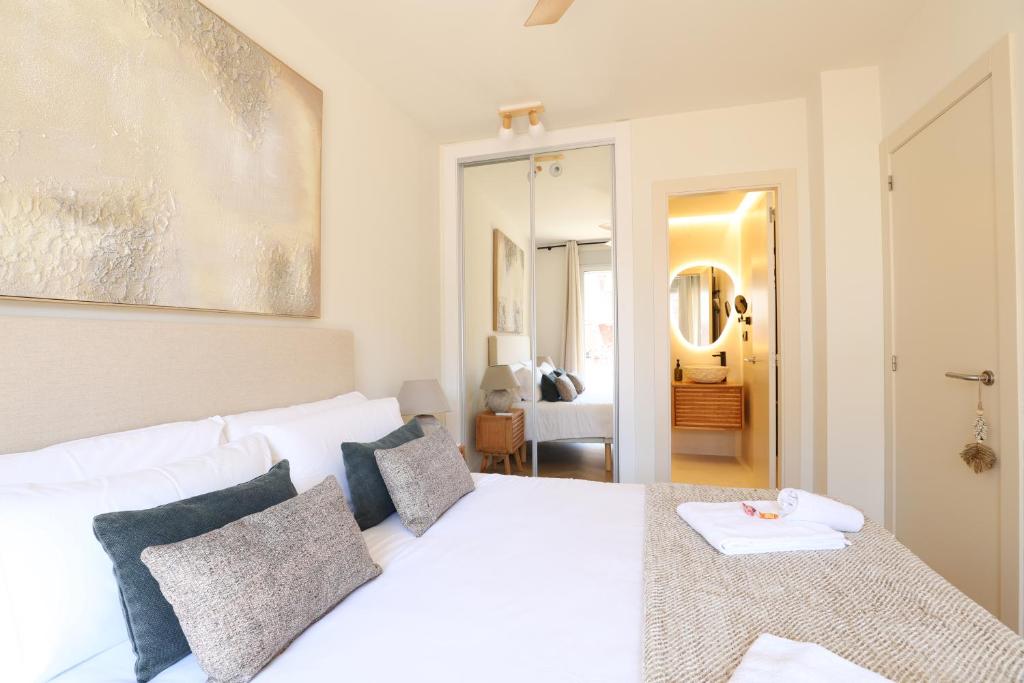 ein weißes Schlafzimmer mit einem großen weißen Bett mit Kissen in der Unterkunft Encantador apartamento junto al Mediterraneo by Hometels in Puerto de Sagunto