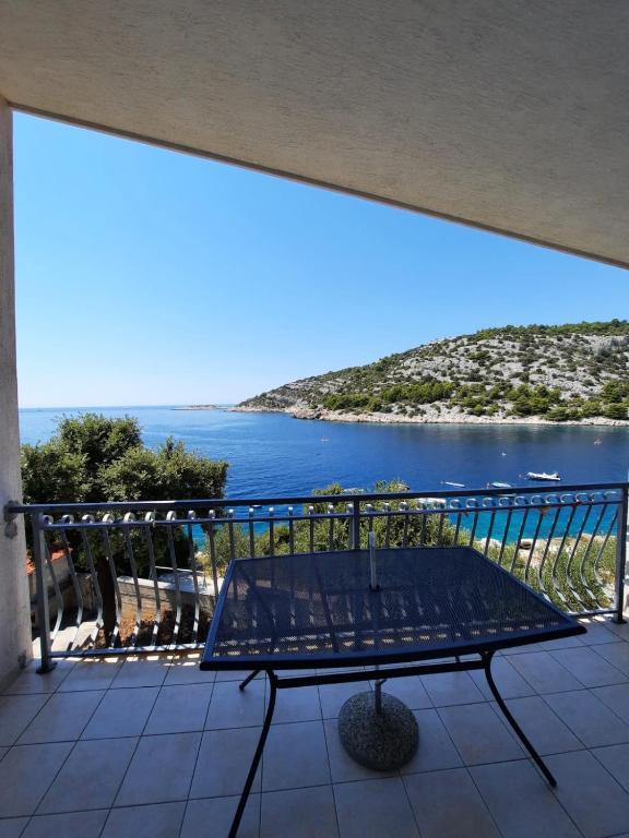 a bench on a balcony with a view of the ocean at Apartman Val in Rogoznica