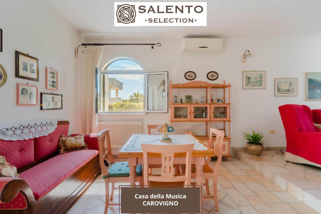 Una sala de estar con una mesa y un sofá rojo. en Casa della Musica - Salento Selection, en Torre Santa Sabina