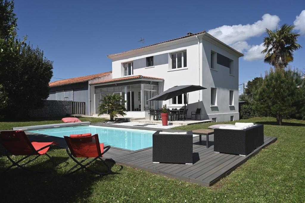 una villa con piscina di fronte a una casa di La Villa Palmier - Piscine avec Grand Jardin a Meschers-sur-Gironde
