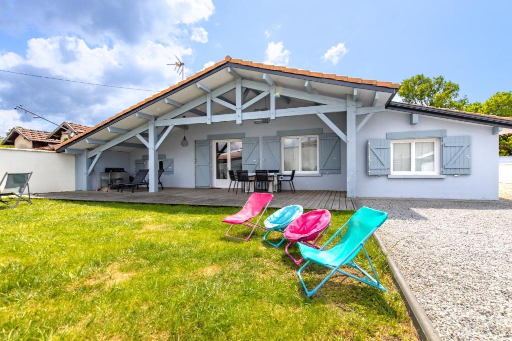 trois chaises assises sur l'herbe devant une maison dans l'établissement La Maison De Mimi 3 étoiles, à Carcans