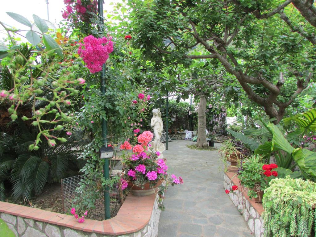a garden filled with lots of flowers and a statue at B&B Palazzo a Mare in Capri