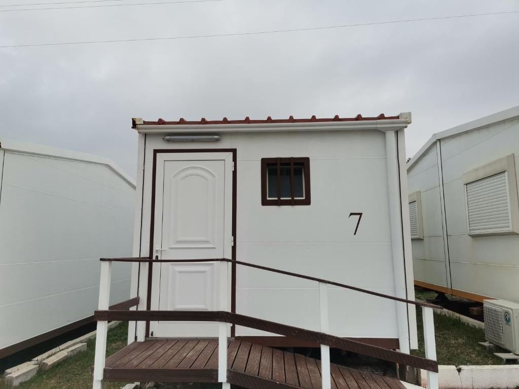 a small white building with a door on a ramp at São Pedro de Moel by Campigir in São Pedro de Moel