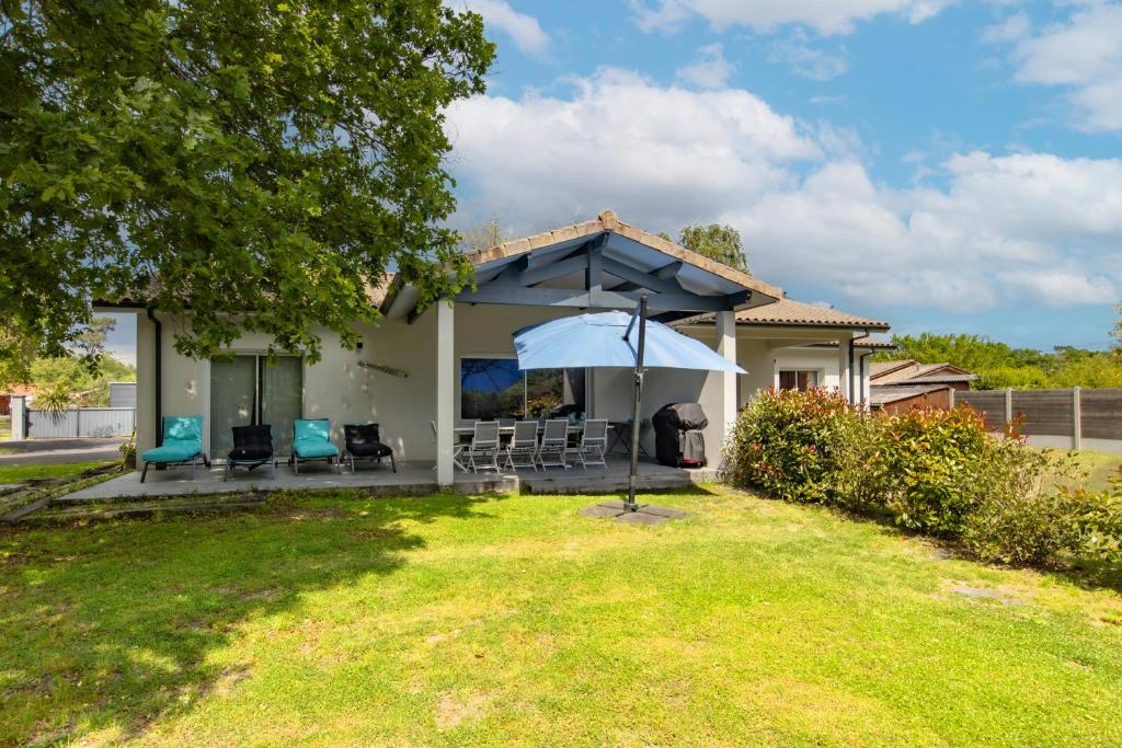 Cette maison dispose d'une terrasse avec des chaises et un parasol. dans l'établissement Villa Atlantica - Grayan, Médoc, à Grayan-et-lʼHôpital