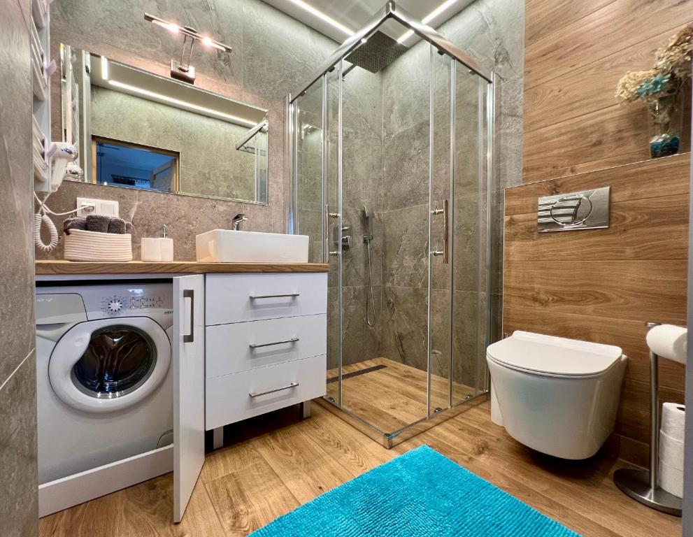 a bathroom with a washing machine and a shower at Domki Odskocznia in Maniowy