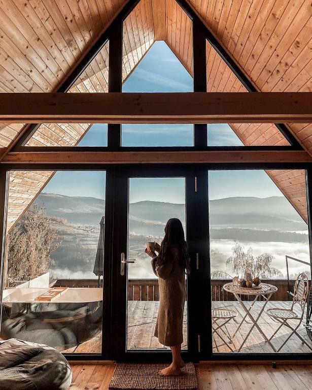 a woman taking a picture of the view from a window at Casa Nordica - La noi la munte in Mătişeşti