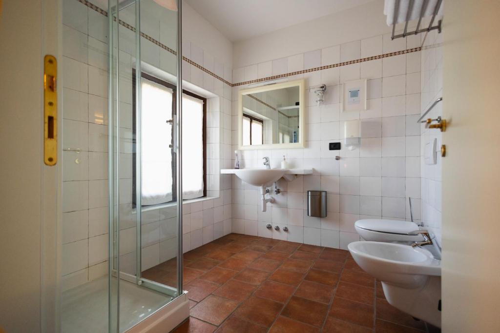 łazienka z 2 toaletami, umywalką i prysznicem w obiekcie Agriturismo Mulino Delle Tolle w mieście Bagnário Arsa